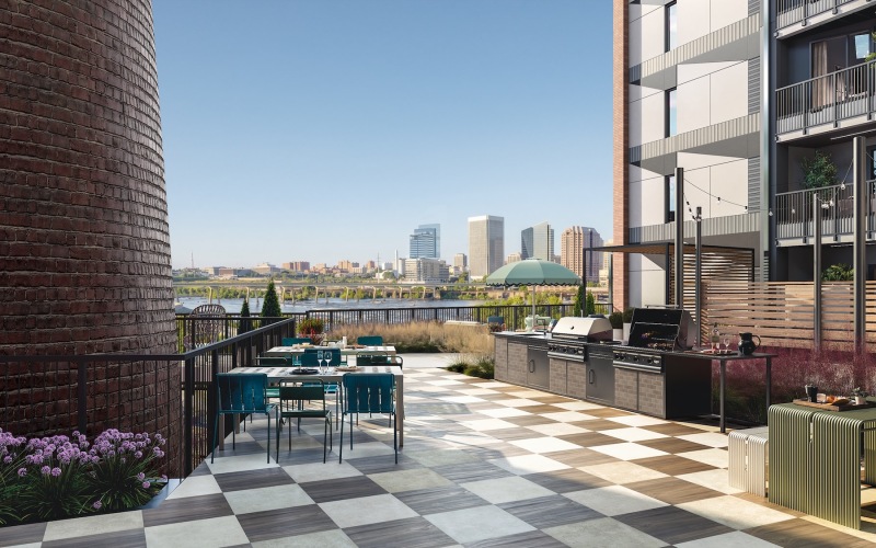 a patio with tables and chairs and a body of water in the background