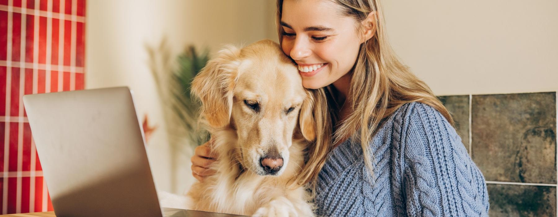 a person and a dog looking at a laptop